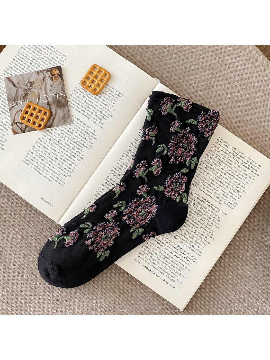 Black sock with raised pink flowers, green leaves and plain toe and heel sections.