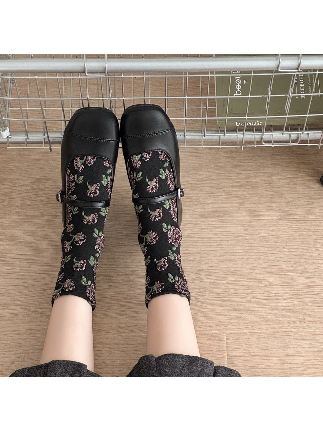 Black floral socks worn with black strap shoes, viewed from above.