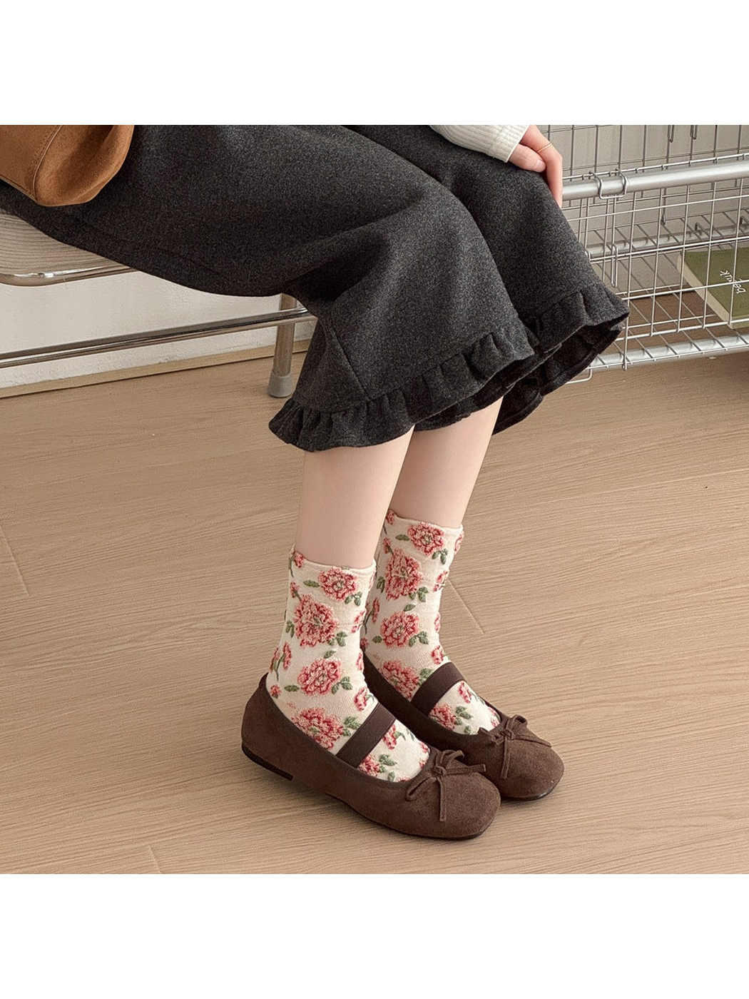 Ivory floral socks worn with brown strap shoes by a seated person.