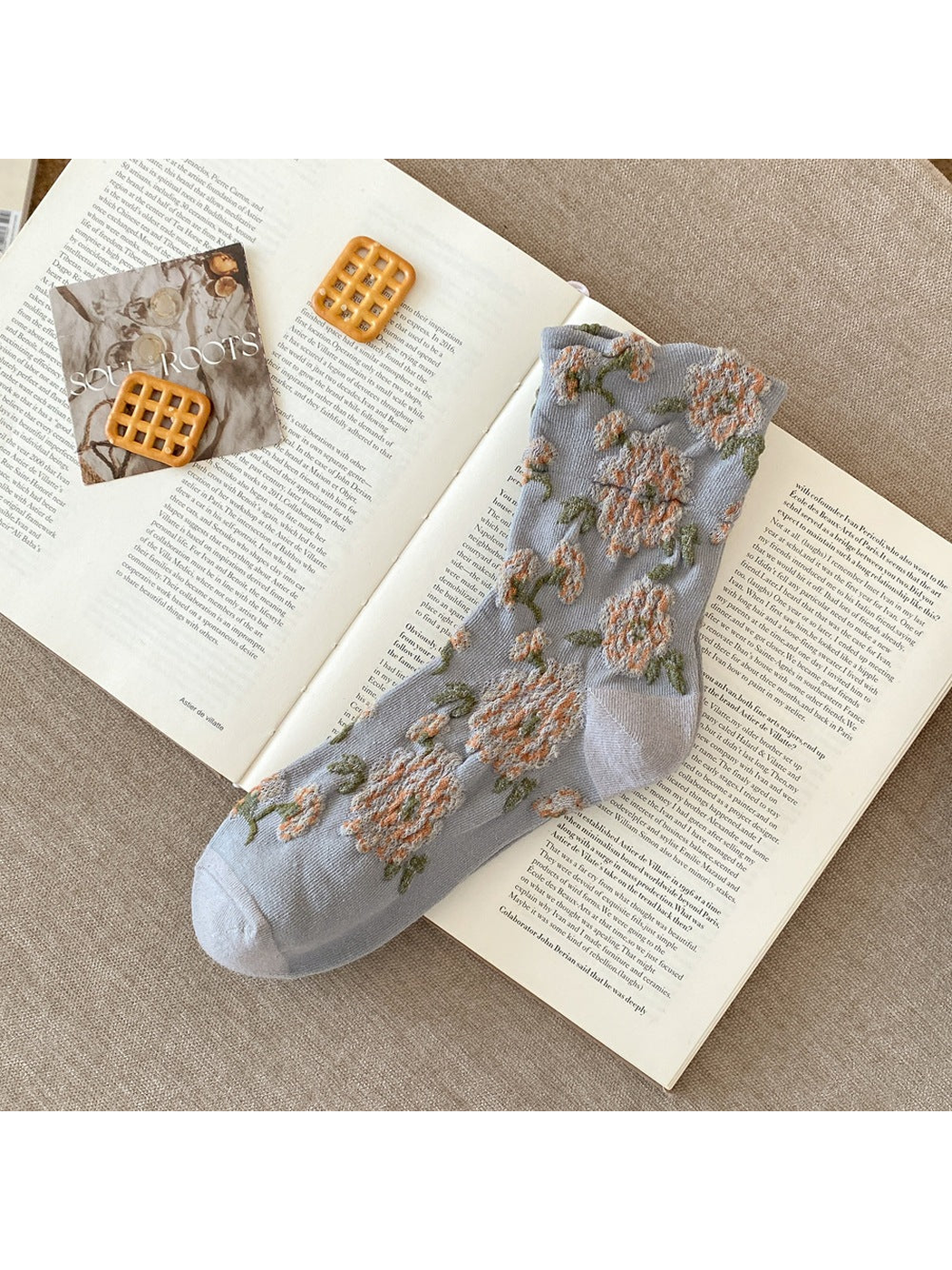 Gray sock with raised peach flowers, green leaves and plain toe and heel sections.