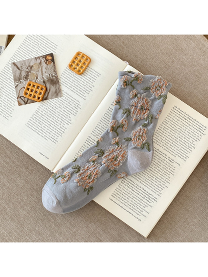 Gray sock with raised peach flowers, green leaves and plain toe and heel sections.