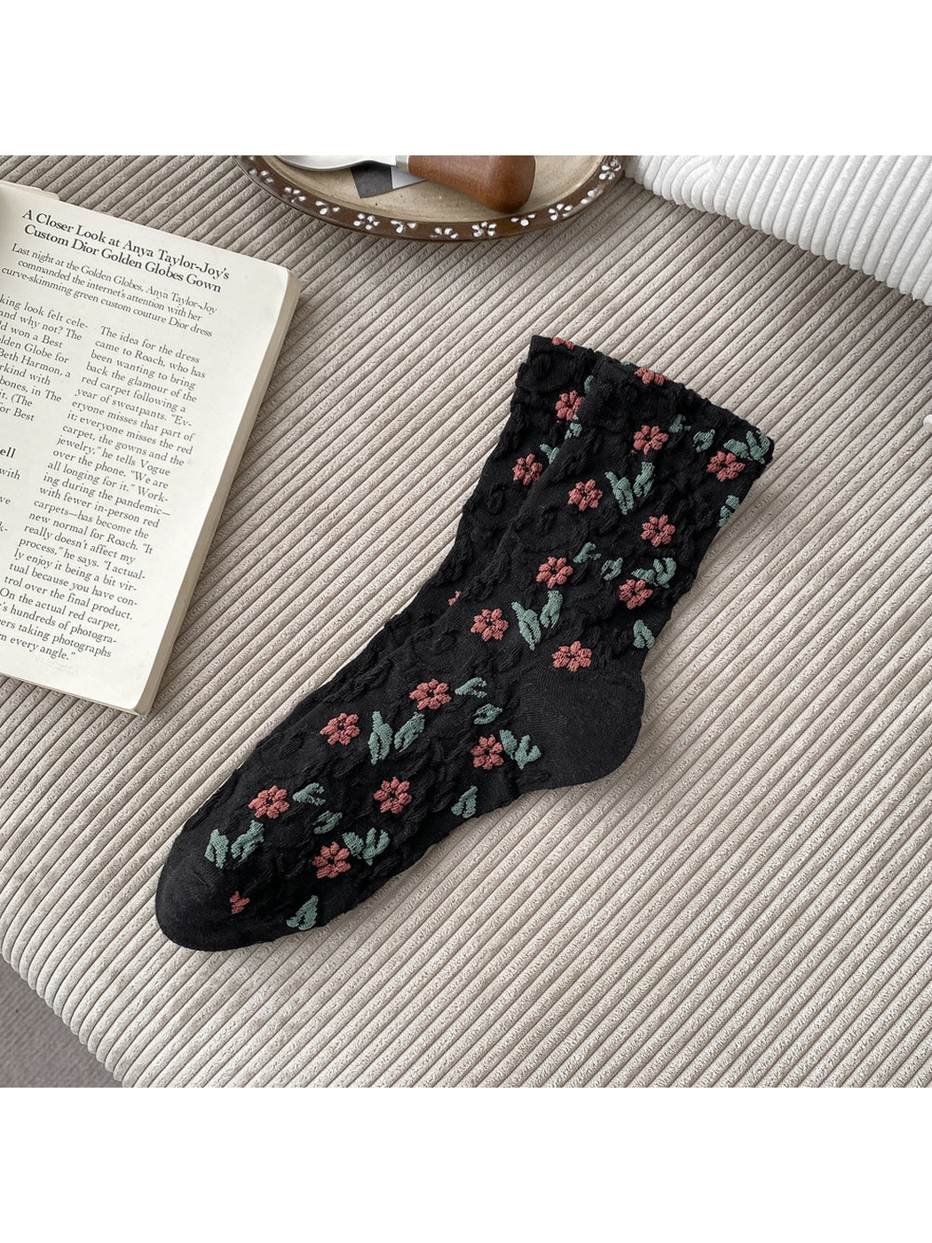 Black socks with pink flowers, green leaves and raised scrolling texture.