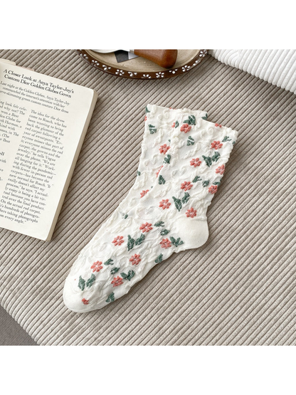 White socks with coral flowers, green leaves and scalloped cuffs.