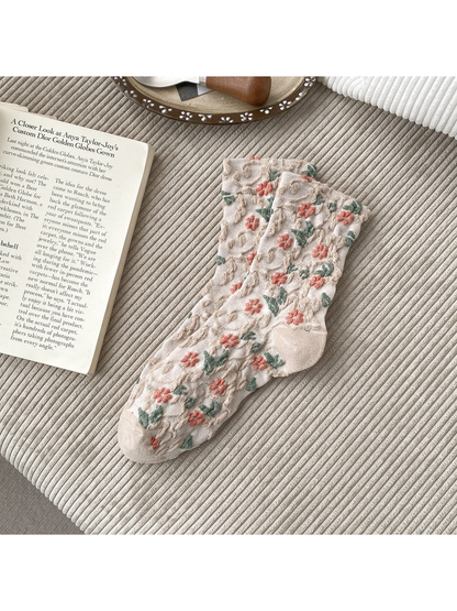 Beige socks with coral flowers, green leaves and raised scrolling texture.