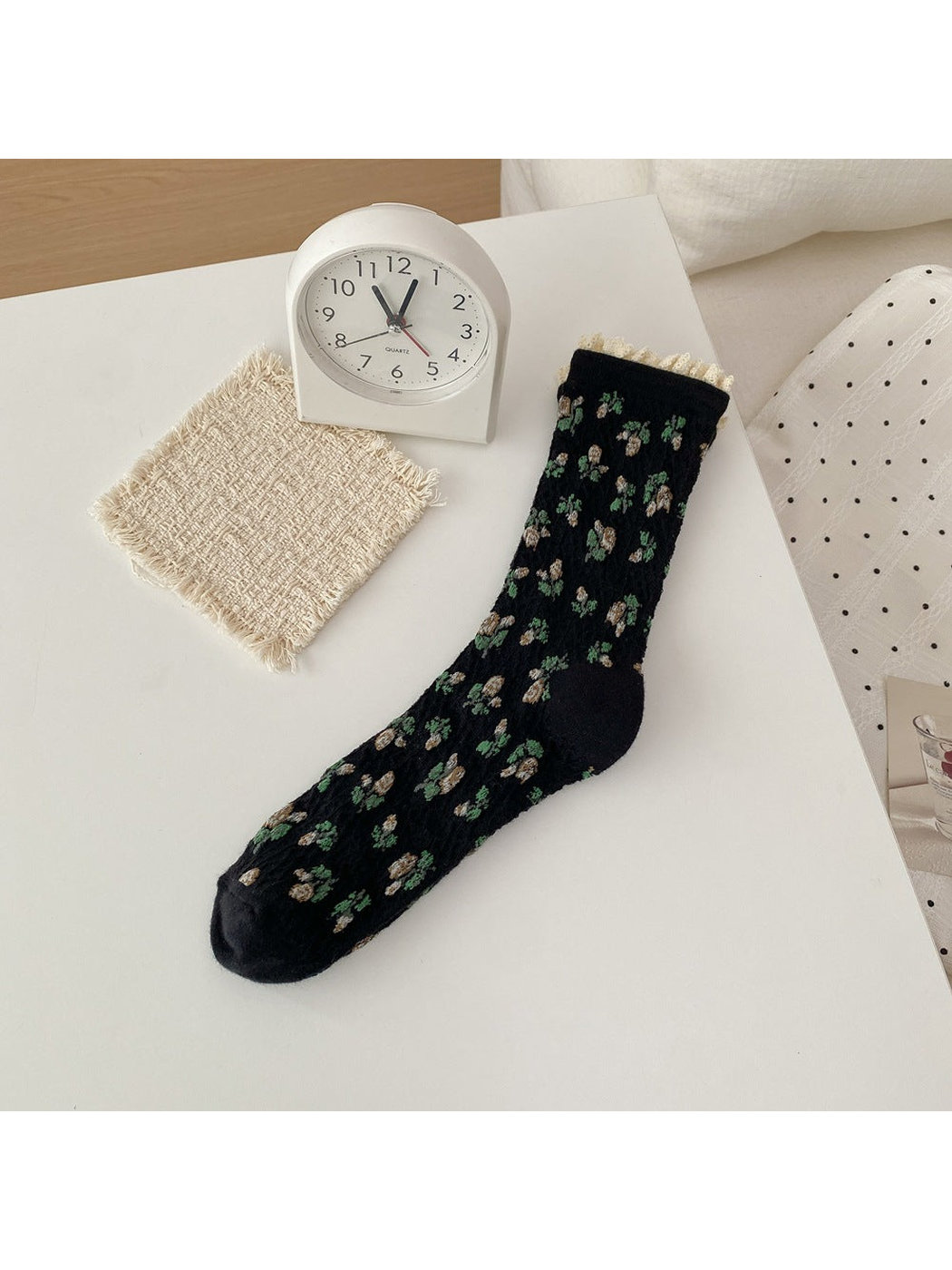 Black sock with cream flowers, green leaves and a cream ruffled cuff.