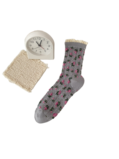 Gray sock with pink flowers, green leaves and a cream ruffled cuff.