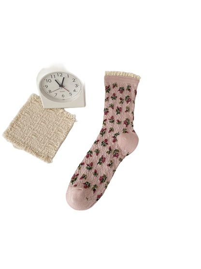 Pink sock with burgundy flowers, green leaves and a cream ruffled cuff.