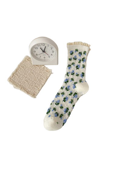 Ivory sock with blue flowers, green leaves and a cream ruffled cuff.