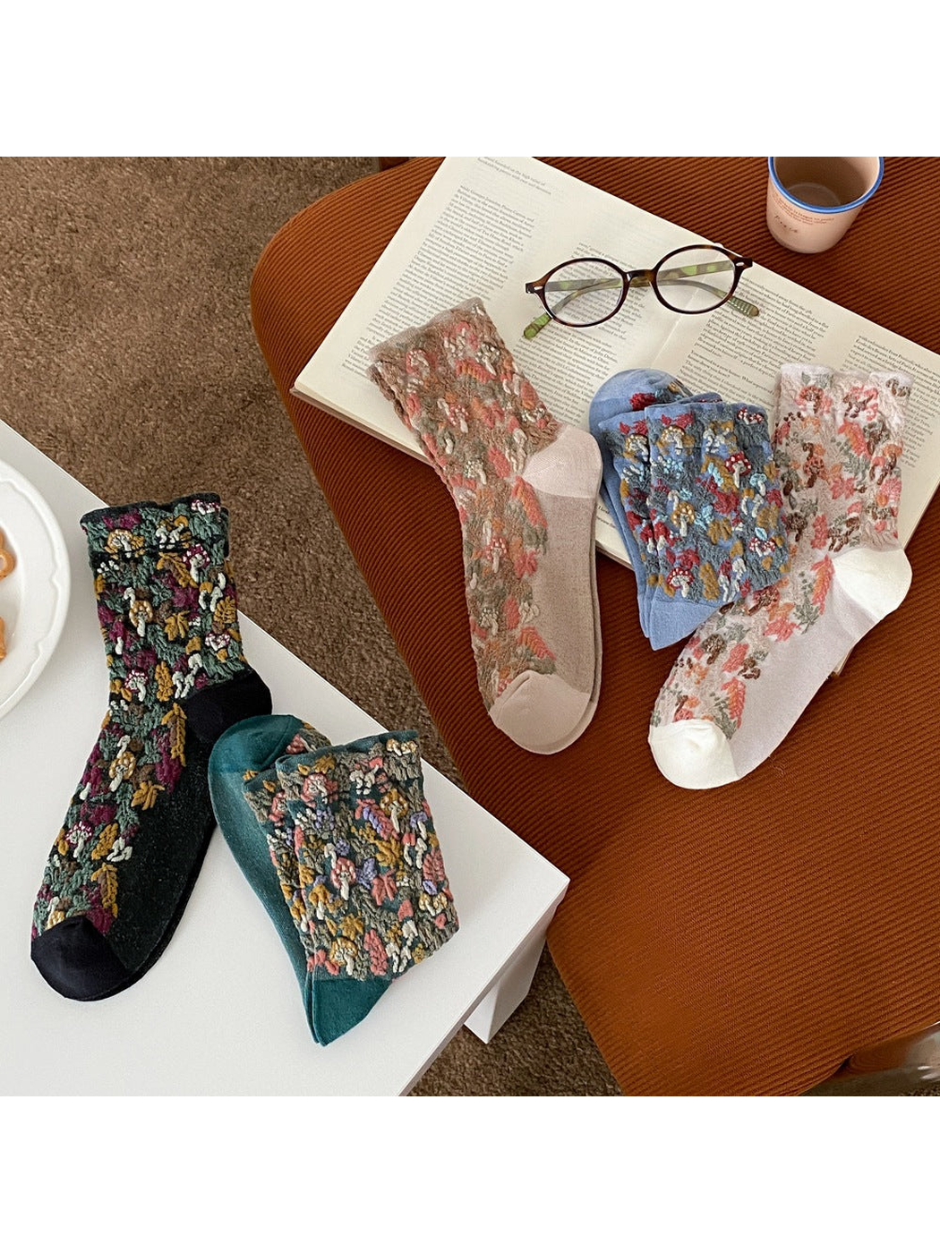 Mushroom and foliage socks arranged across a table and chair in five colors.