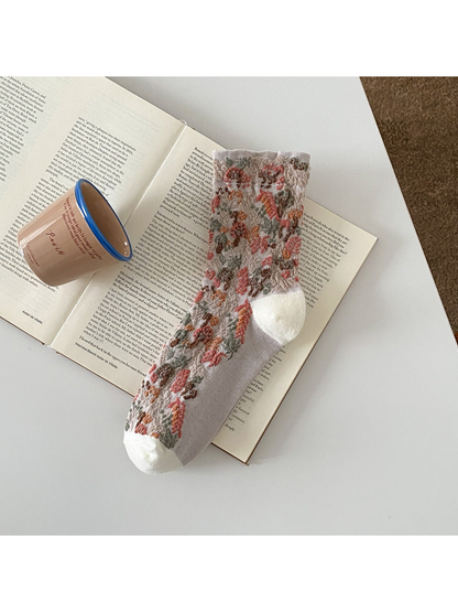 Beige sock with raised mushroom and foliage motifs and a ribbed cuff.