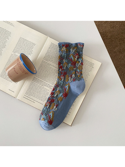 Blue sock with raised mushroom and foliage motifs and a ribbed cuff.