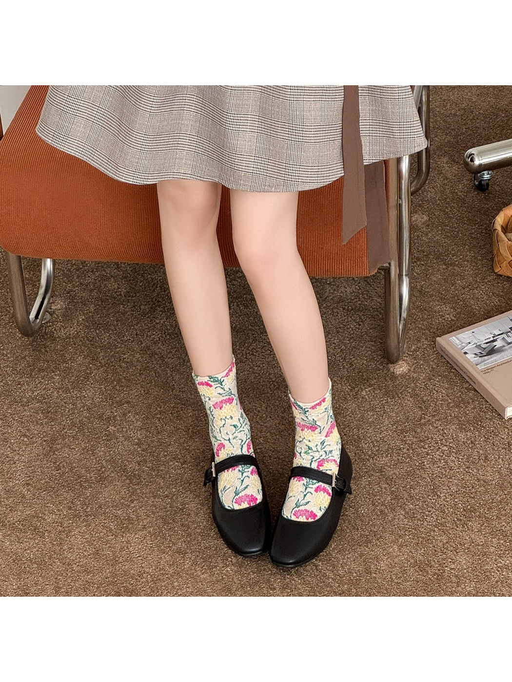 Beige floral socks worn with black strap shoes beneath a plaid skirt.