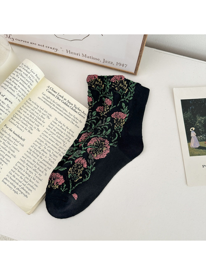 Black floral sock laid flat with pink flowers and green leaves.