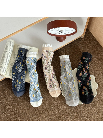 Floral socks in Navy, Blue, Cream, Gray and Black with diamond patterns and ruffled cuffs.