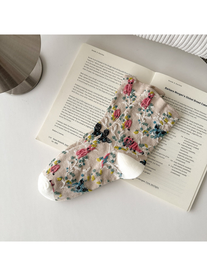 Beige socks with animal and botanical patterns and white toes and heels.