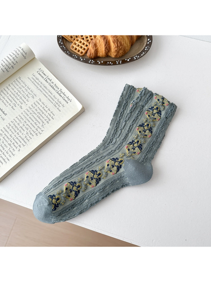 Green socks laid flat with repeating floral medallions, textured vertical ribbing and shaped heels.
