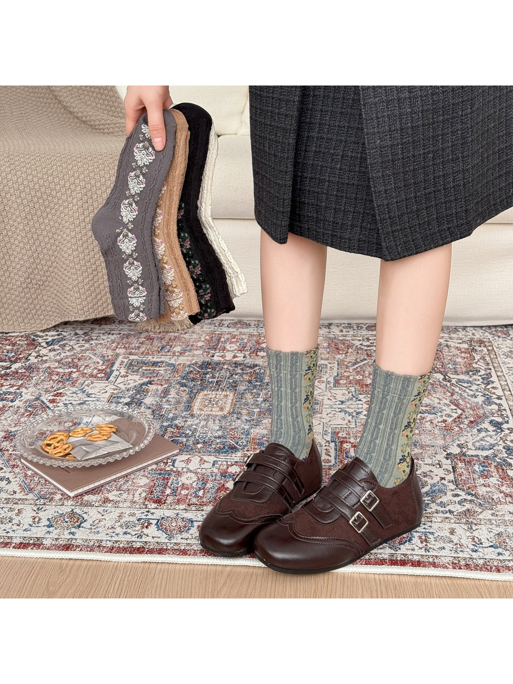 Green patterned socks worn with brown buckle shoes, with other sock colors held beside them.