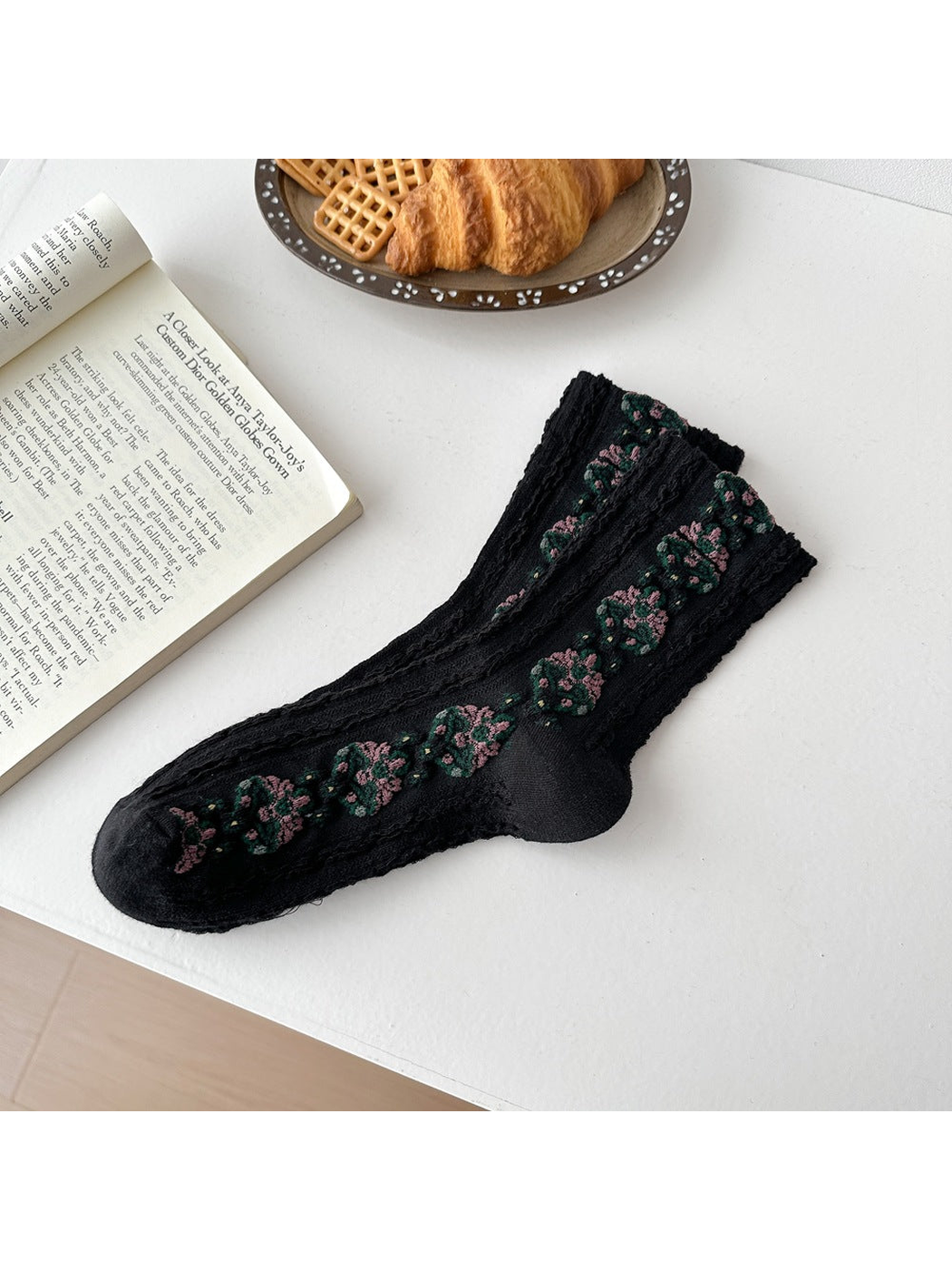 Black socks laid flat with repeating floral medallions and textured vertical ribbing.