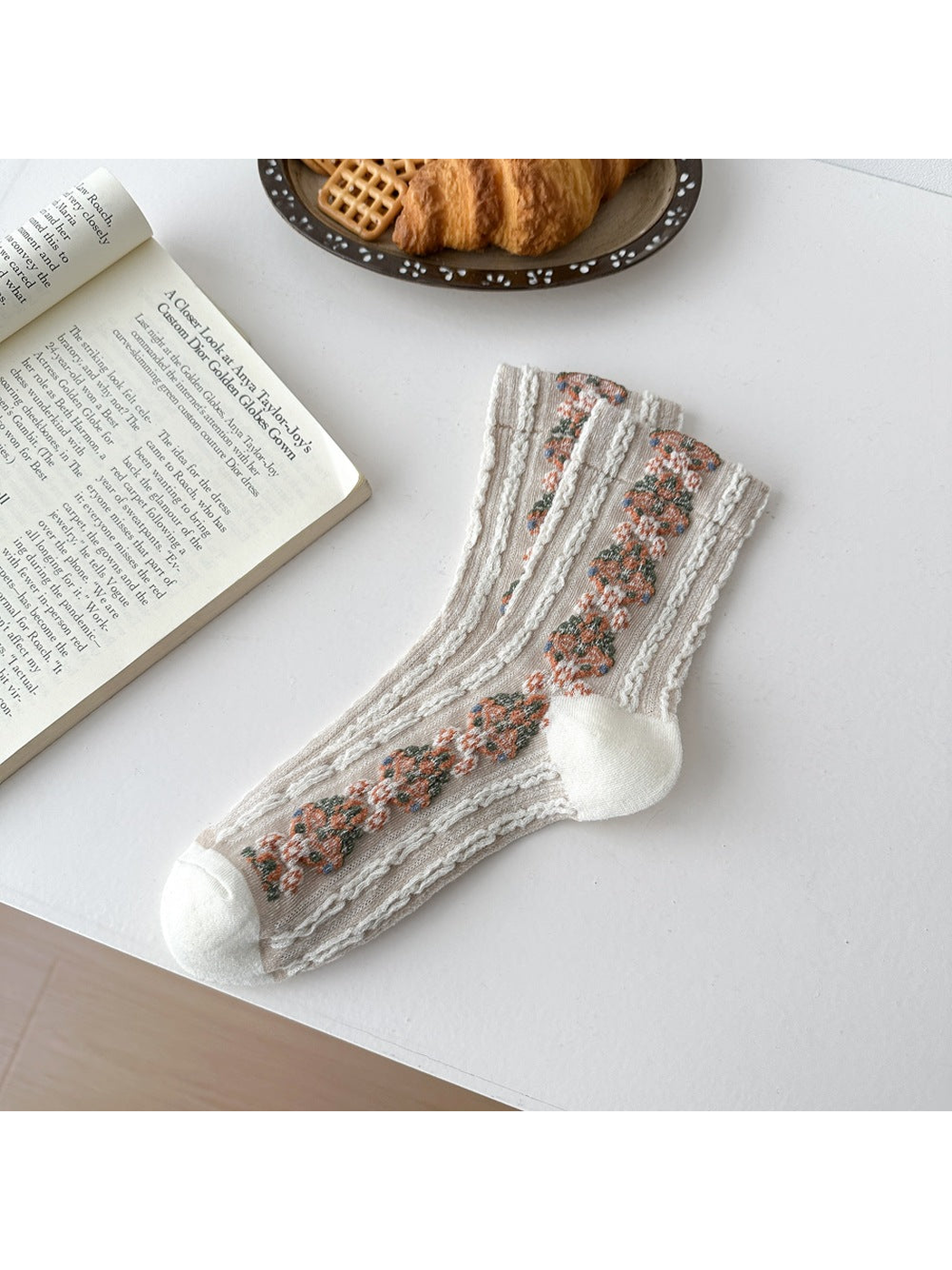 Ivory socks laid flat with repeating floral medallions and textured vertical ribbing.