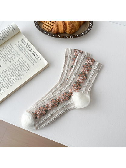 Ivory socks laid flat with repeating floral medallions and textured vertical ribbing.
