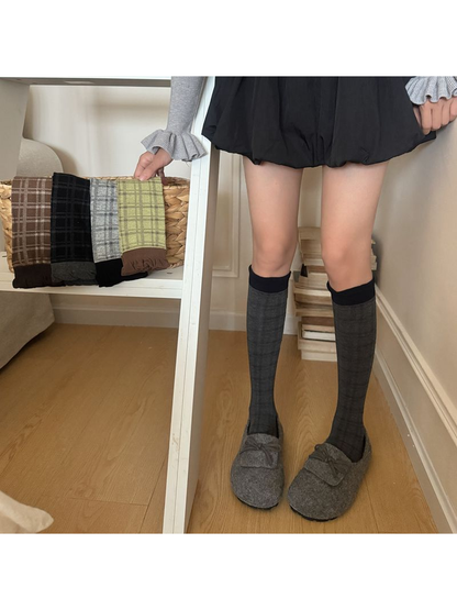 Dark Gray plaid socks worn with gray shoes, with other sock colors displayed nearby.