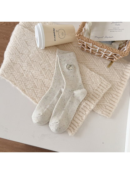 Ivory ribbed socks with a yellow checked dog motif and multicolored flecks.