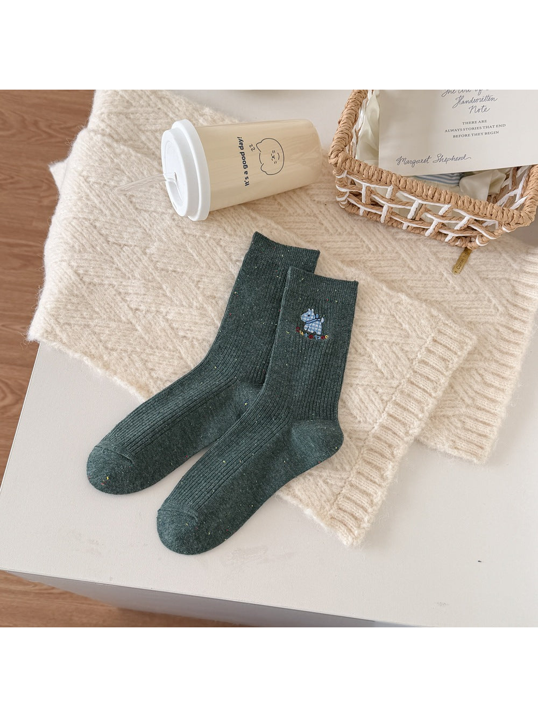 Green ribbed socks with a blue checked dog motif, multicolored lettering and flecks.