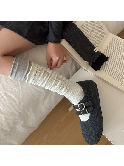 Side view of an ivory patterned sock worn with a dark double-buckle shoe.