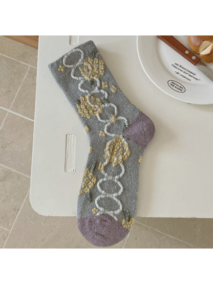 Gray sock with yellow floral clusters, ivory linked ovals, and purple heel and toe panels.