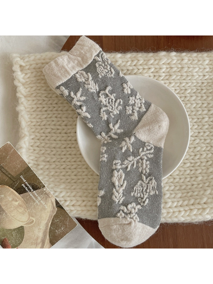 Gray sock with raised ivory flowers and a contrasting ivory cuff, heel and toe.