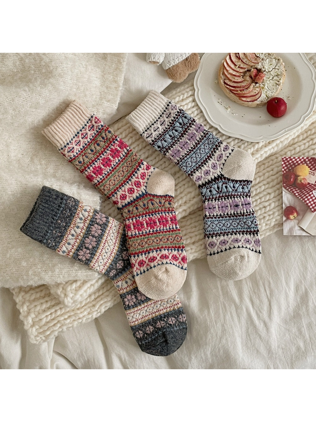 Blue, Gray and Red patterned socks arranged on cream textiles.