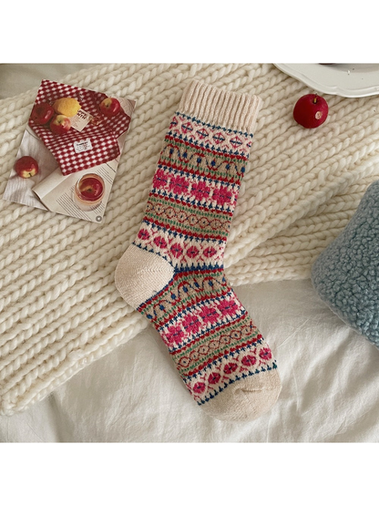 Red patterned sock with floral and geometric bands and a cream ribbed cuff, heel and toe.