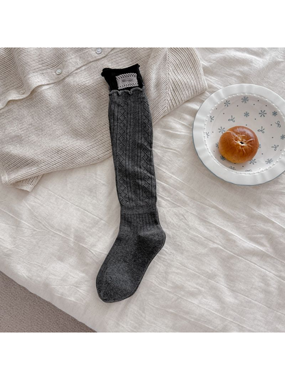 Gray pointelle sock laid flat with a black upper cuff, pale rectangular patch, and scalloped edging.