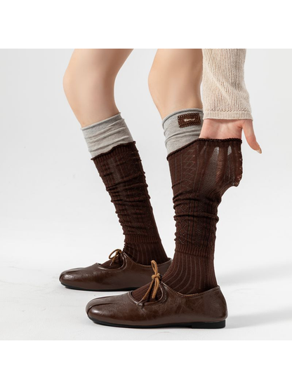 Brown pointelle socks worn with brown shoes, with one leg section pulled outward to show the textile.
