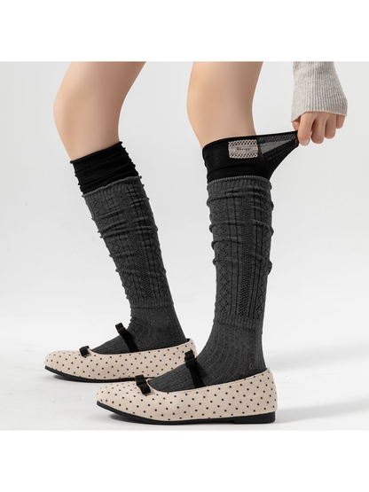 Gray pointelle socks worn with dotted shoes, with one black upper cuff pulled outward.
