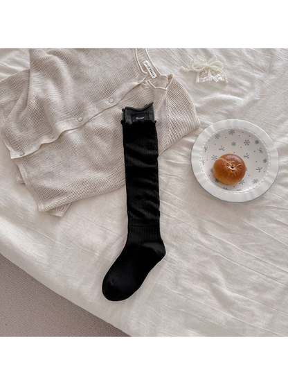 Black sock laid flat with a contrasting gray cuff and rectangular patch.