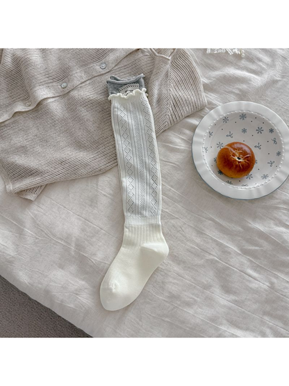 White pointelle sock laid flat with a gray cuff, white patch, and ribbed ankle section.