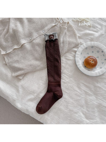 Brown pointelle sock laid flat with a gray upper cuff, brown patch, and ribbed ankle section.