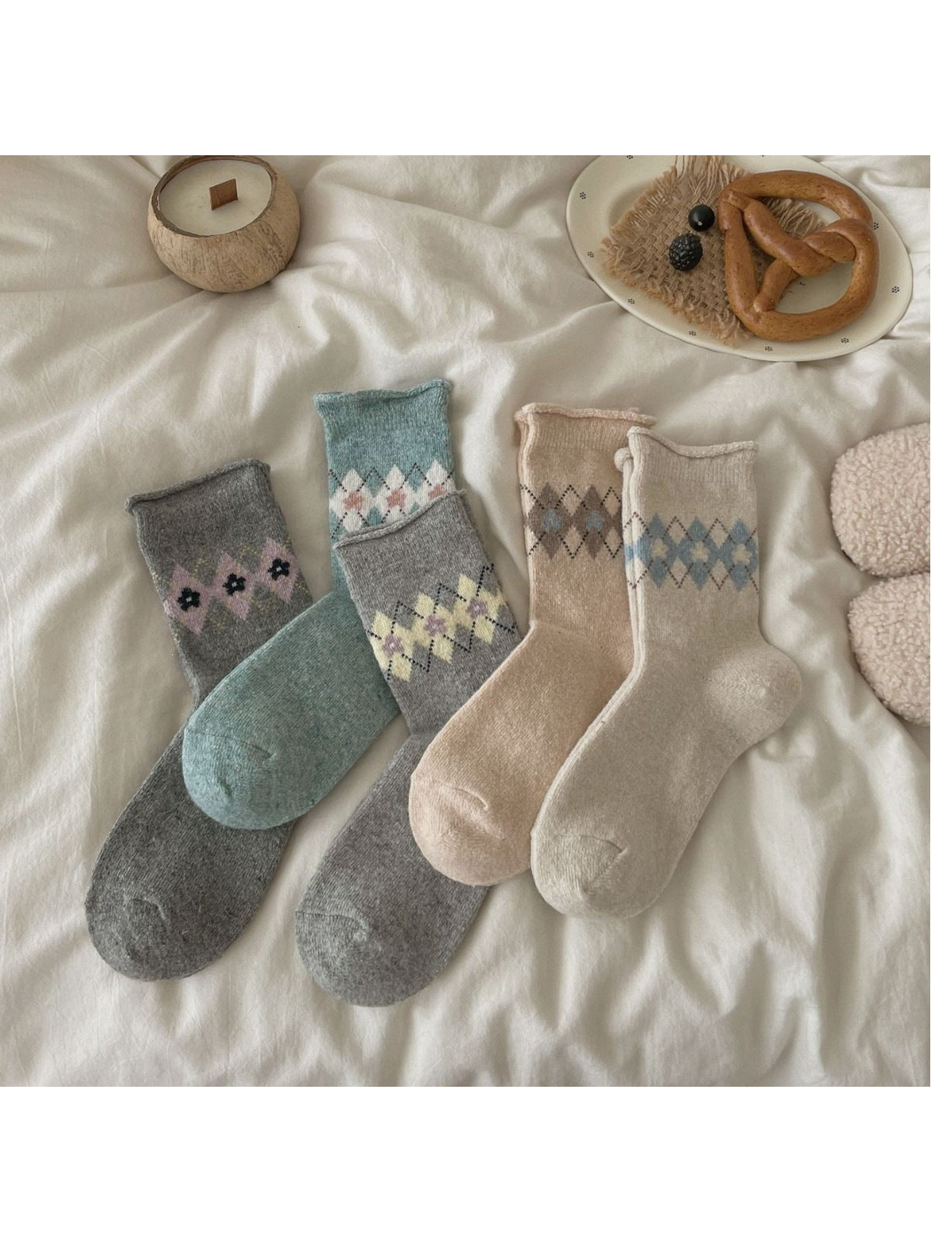 Five floral and dotted diamond sock colorways arranged on ivory fabric.