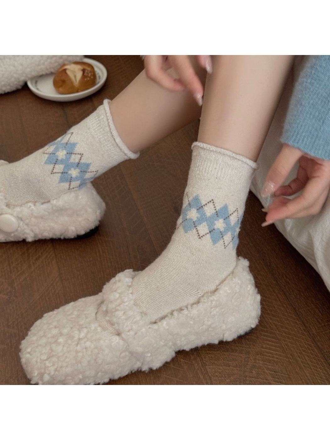 Ivory socks with blue flowers and dotted diamonds worn with textured slippers.