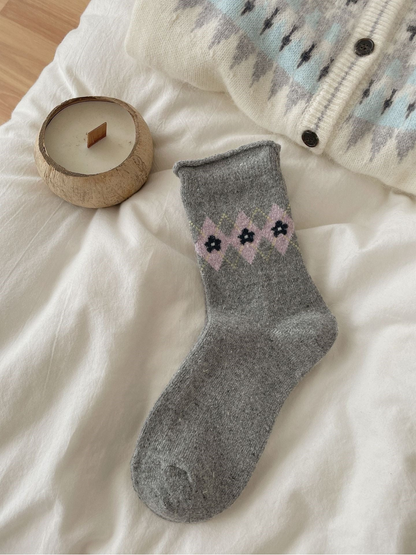 Gray sock with pink flowers, black centers, dotted diamonds, and a rolled cuff.