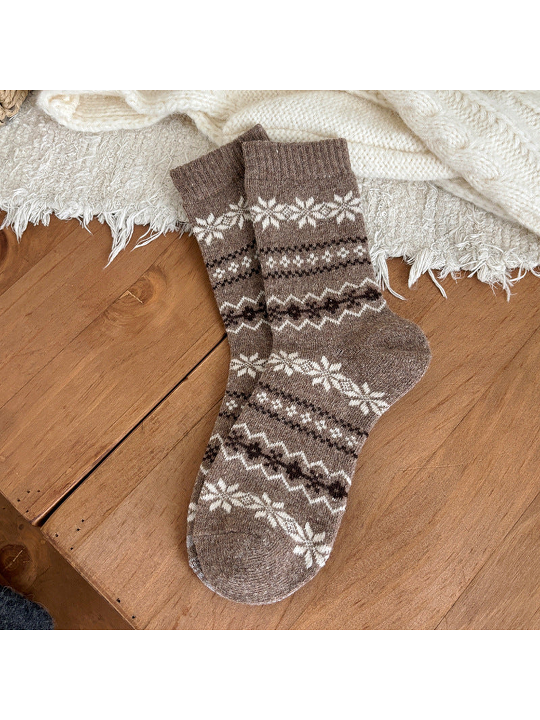 Greige socks with snowflake and geometric bands and ribbed cuffs on a wooden surface.