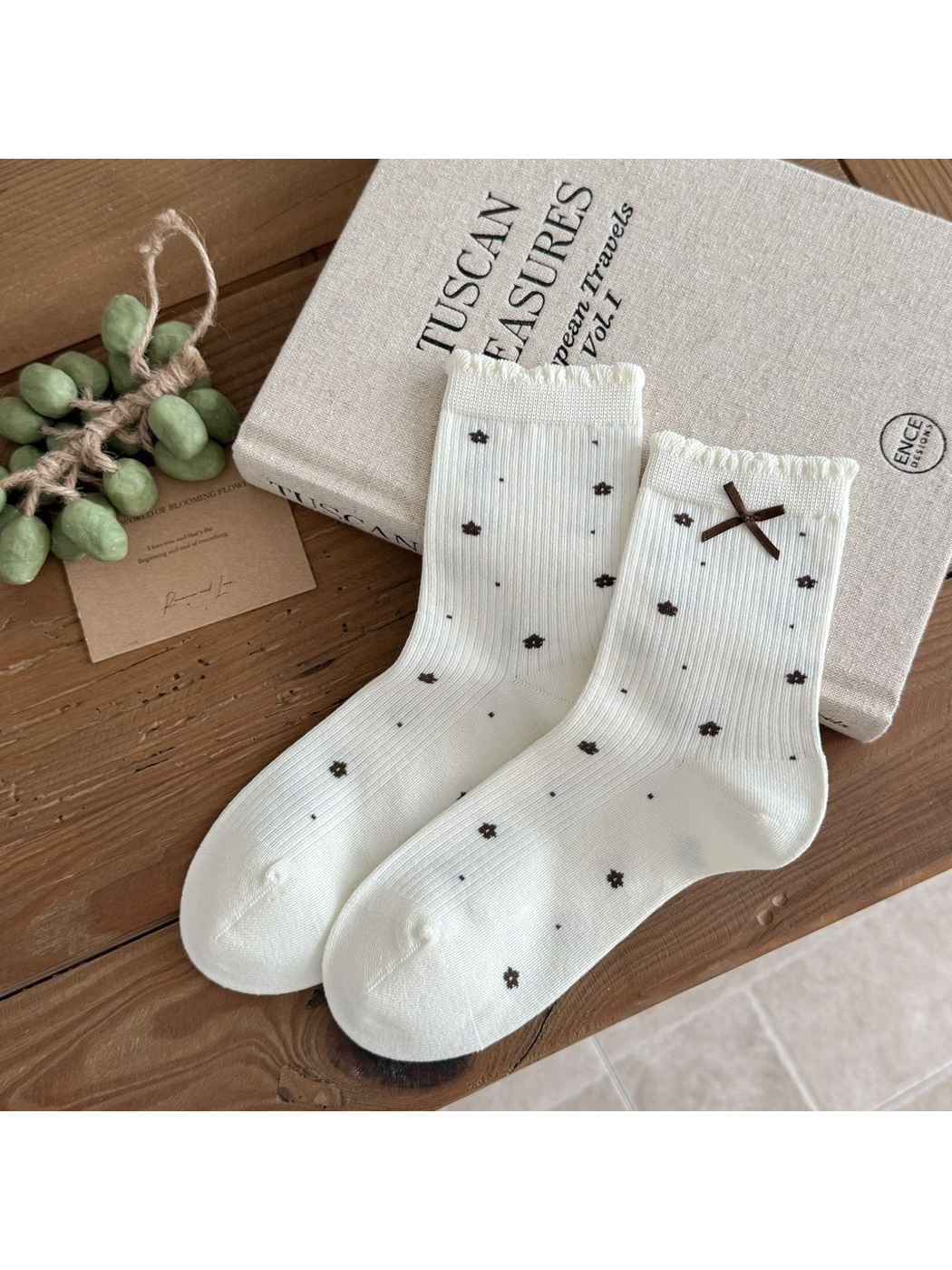 Ivory Flowers socks with dark floral motifs, vertical ribbing, scalloped cuffs and a brown ribbon bow.