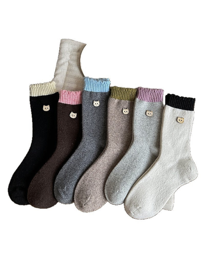 Socks in six color combinations with contrasting ribbed cuffs and cat face emblems on a white background.