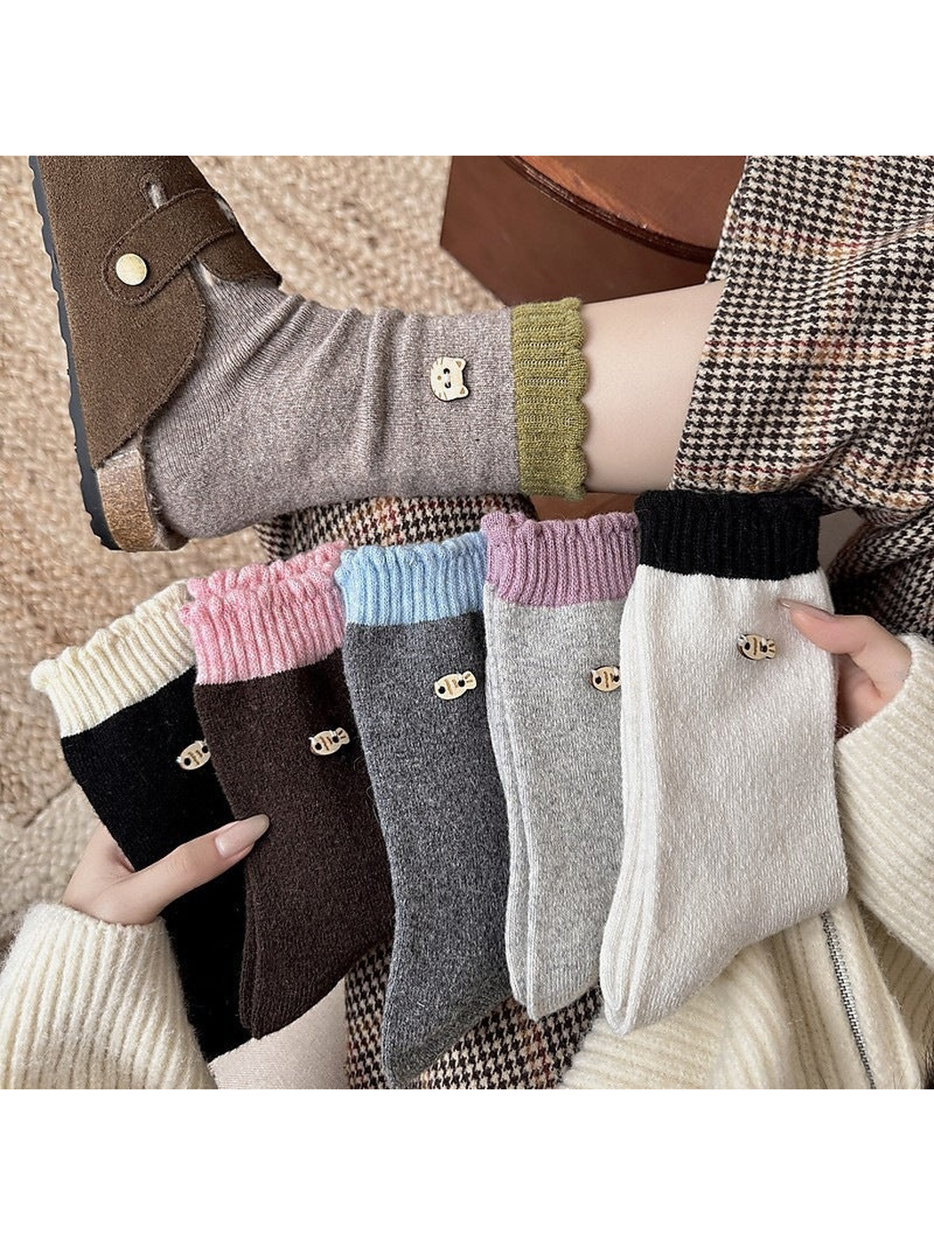 Socks with contrasting ribbed cuffs and decorative emblems held beside a worn sock.