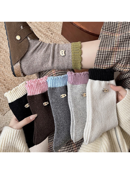 Socks with contrasting ribbed cuffs and decorative emblems held beside a worn sock.