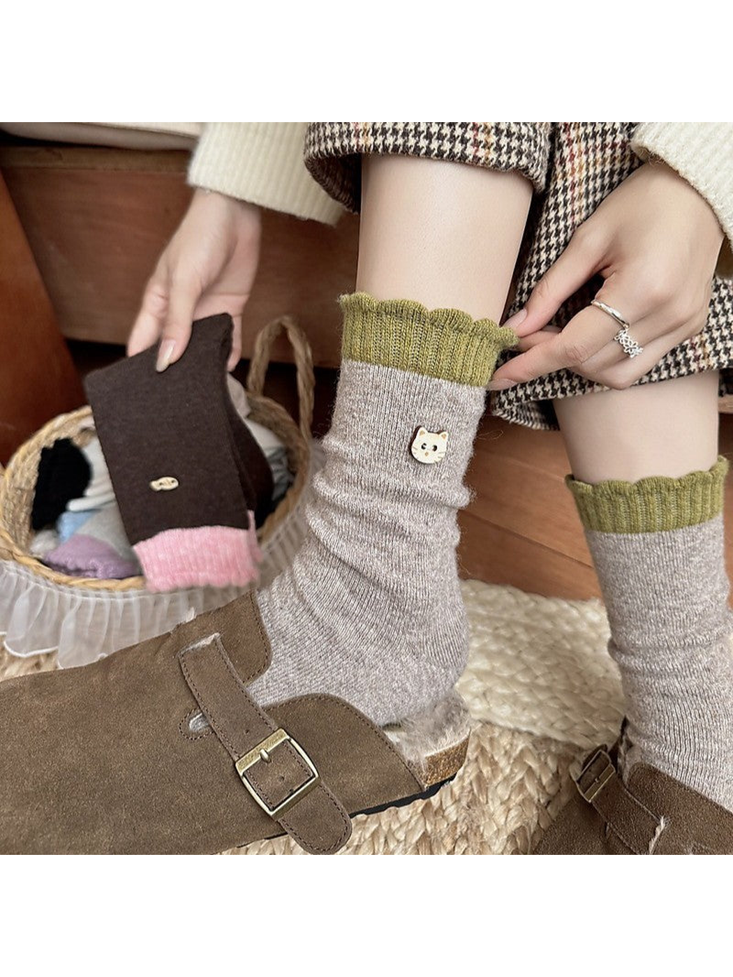 Person adjusting a green cuff on socks worn with brown clogs while holding a brown sock.