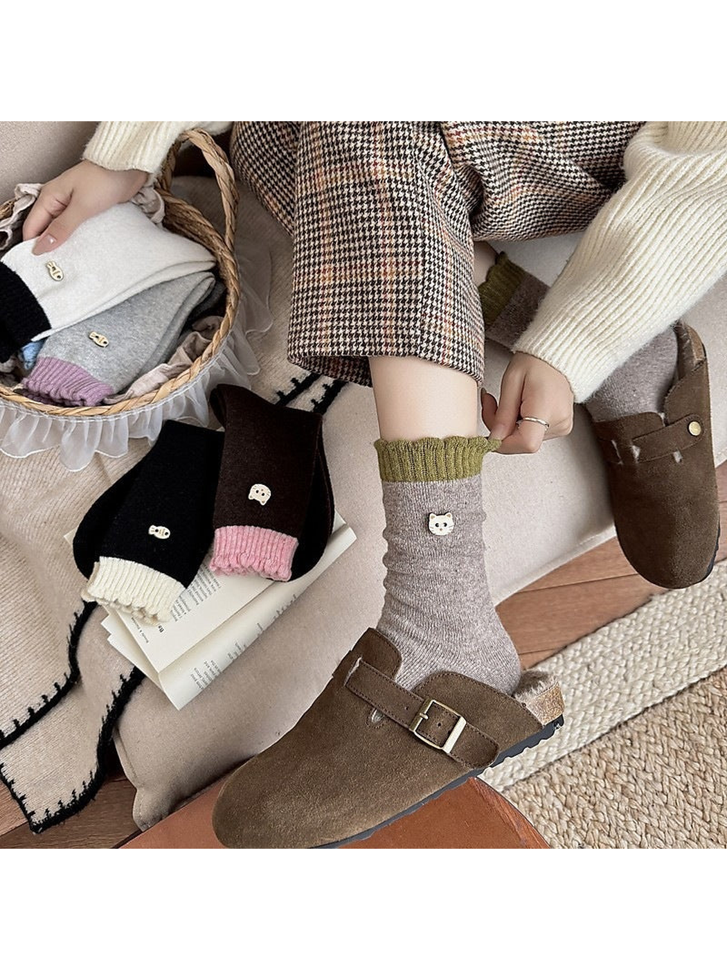 Seated person adjusting a green sock cuff above a brown clog, with other socks nearby.