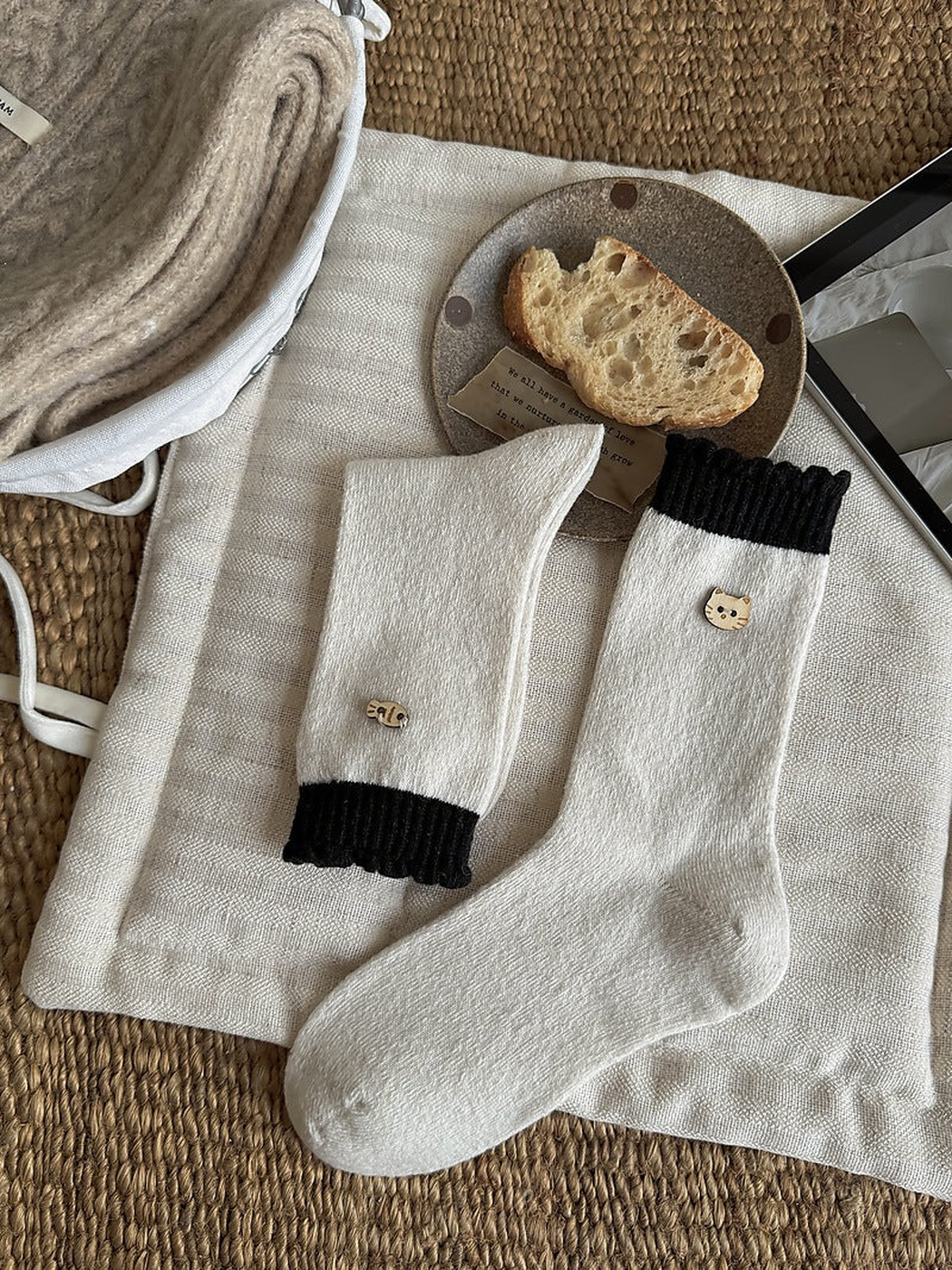 White socks with black ribbed cuffs and cat face and fish emblems, shown flat and folded.