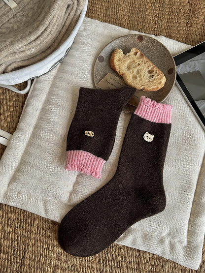 Brown socks with pink ribbed cuffs and cat face and fish emblems, shown flat and folded.